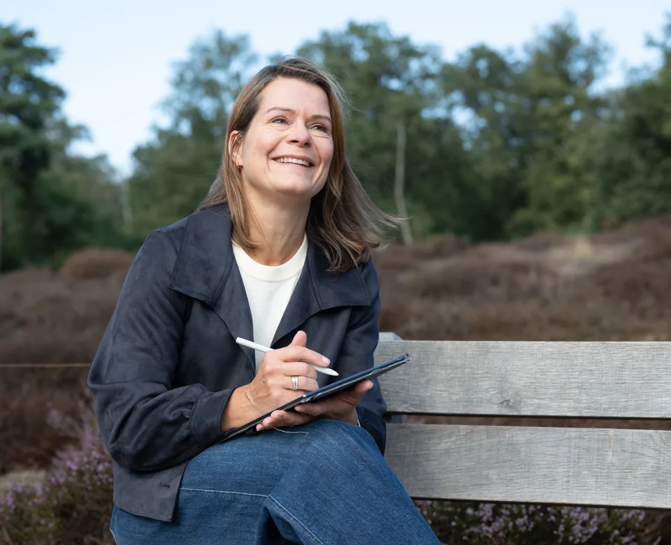 Jannie Hopman met een notitieboek op een bankje